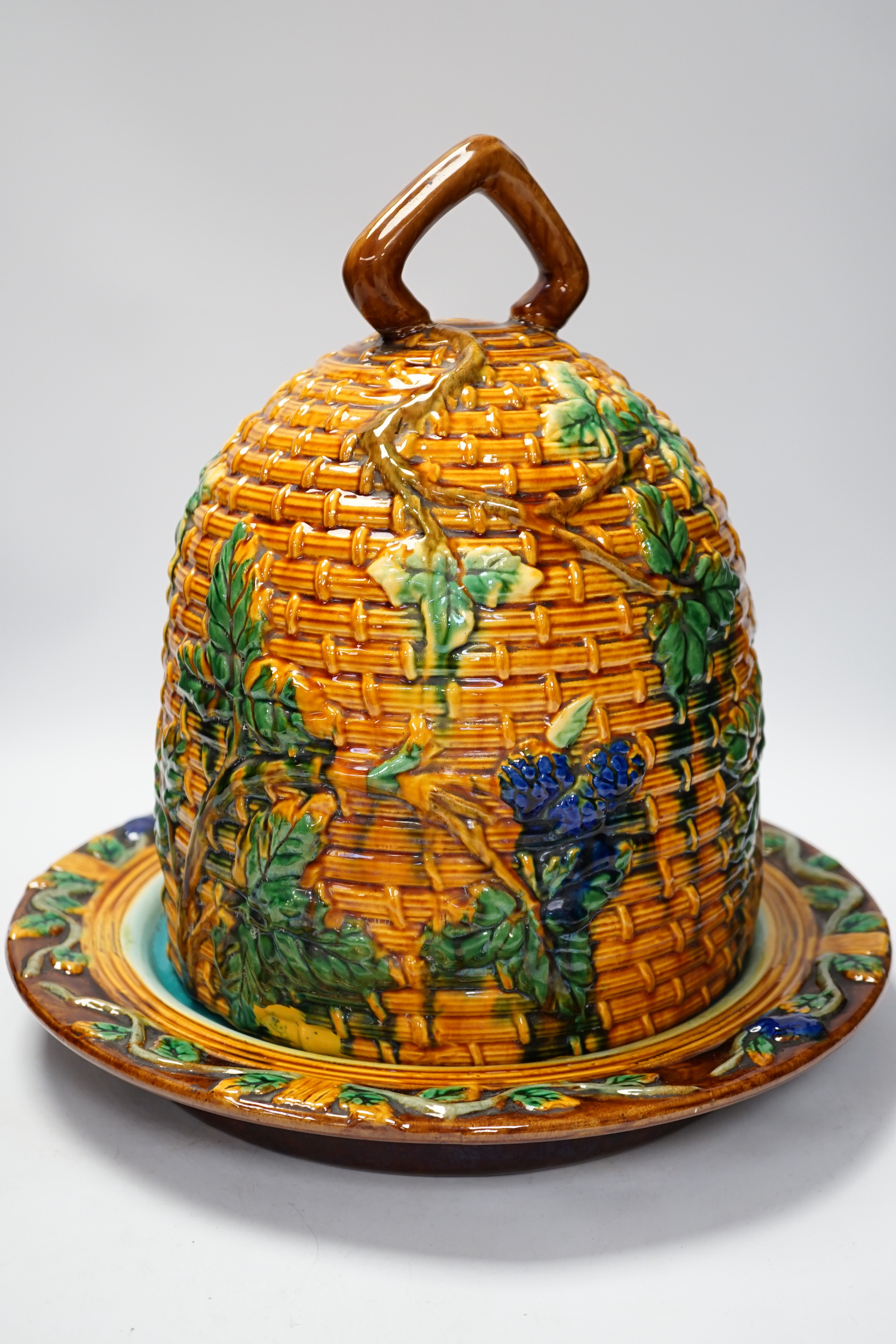 A Minton style Majolica cheese dish and cover decorated in relief, restored handle, 35cm